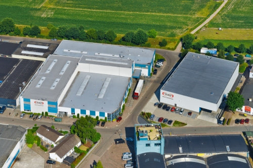 An aerial photograph shows the technivorm factory, painted blue and white. Green fields expand beyond.