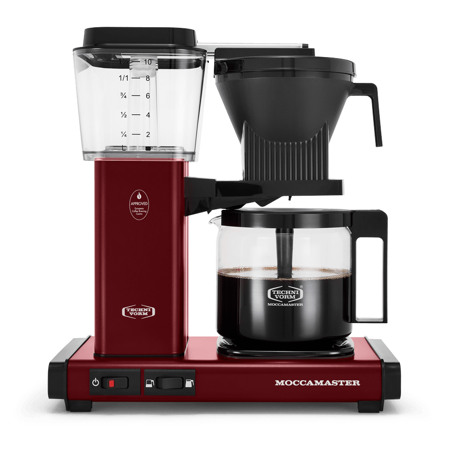Front shot showing Moccamaster KBGV Select in Merlot, with rectangular tower and base, clear acrylic water reservoir with fill level marks, power and volume selector switch, glass carafe with black handle, and black automatic brew basket.