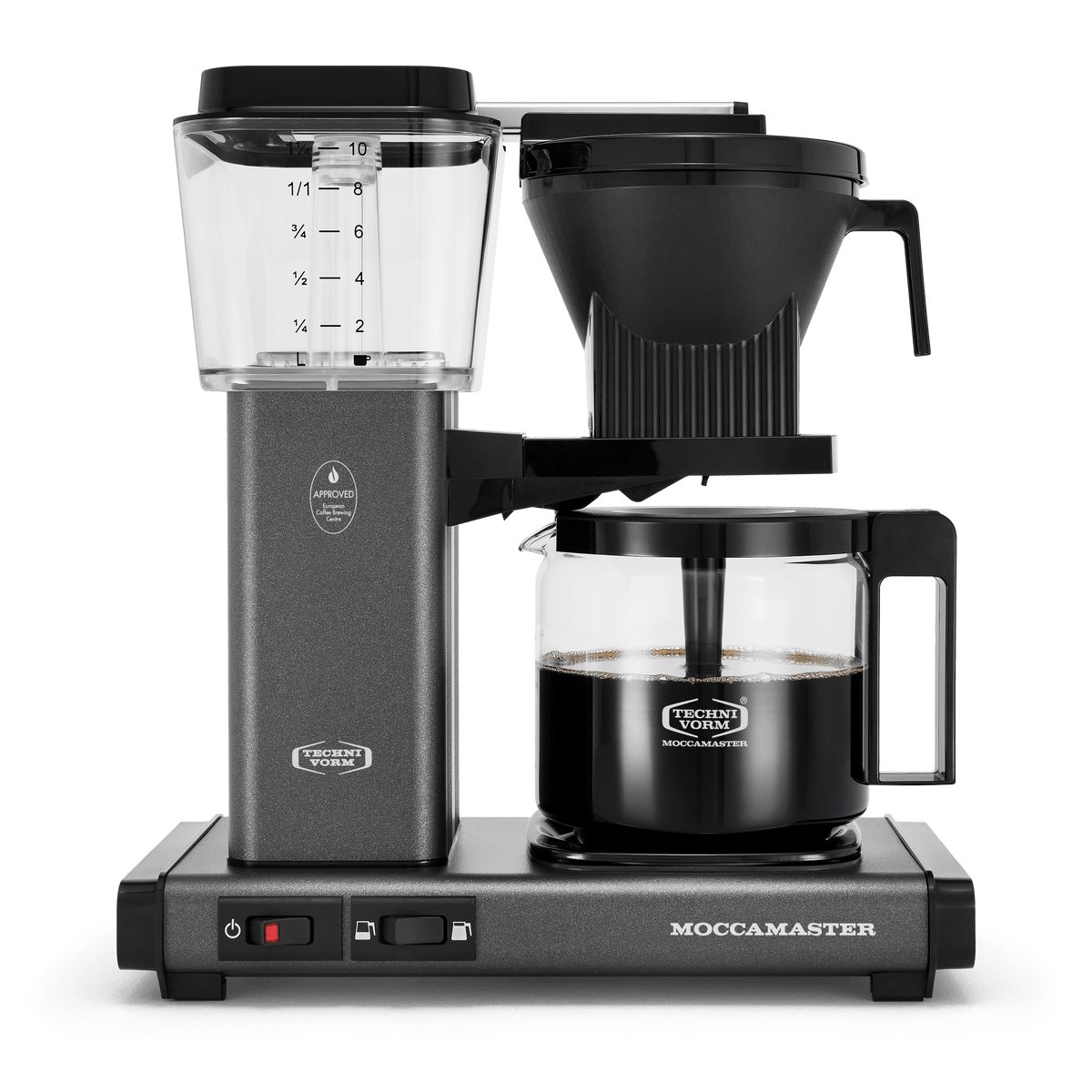 Front shot showing Moccamaster KBGV Select in Stone Grey, with rectangular tower and base, clear acrylic water reservoir with fill level marks, power and volume selector switch, glass carafe with black handle, and black automatic brew basket. 