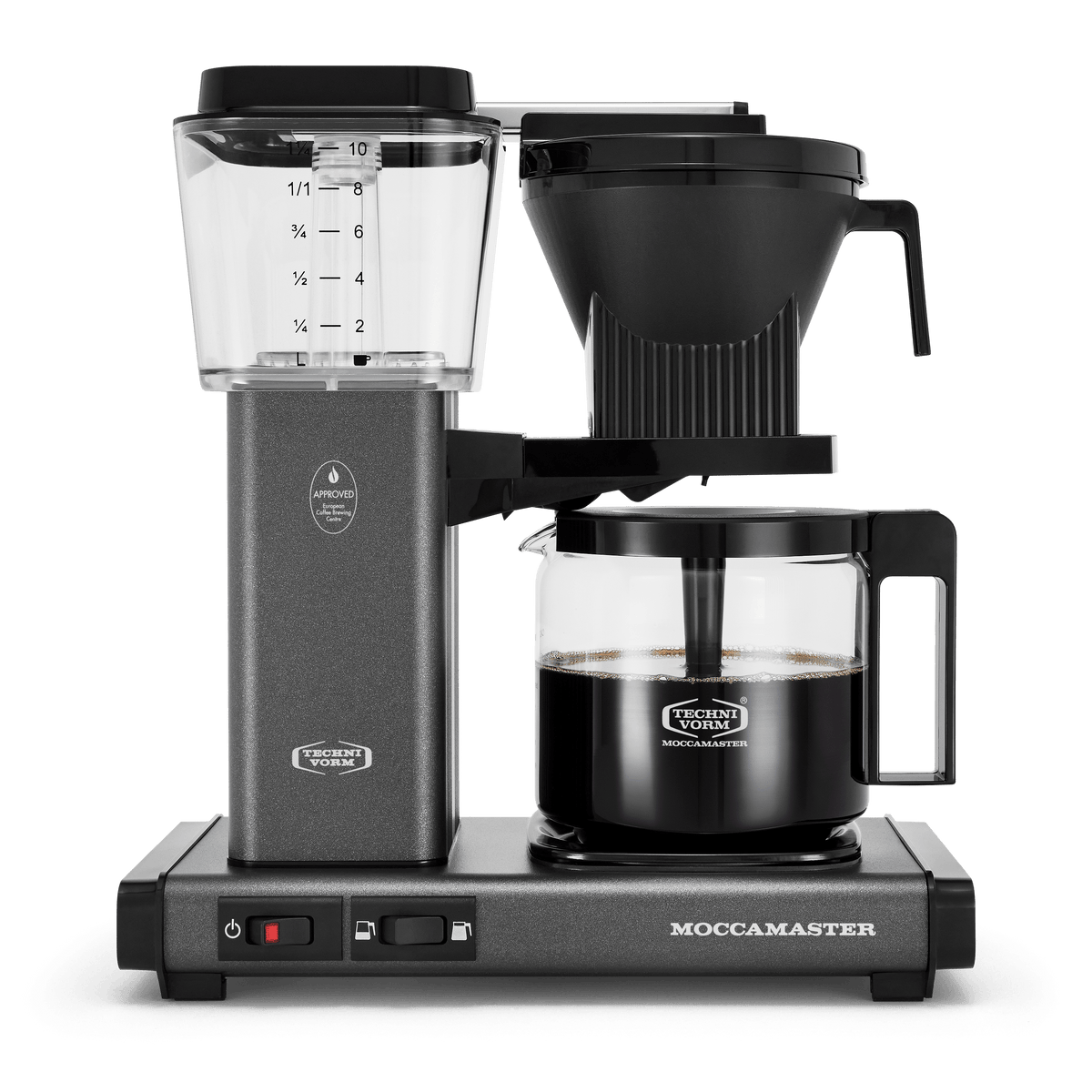 Front shot showing Moccamaster KBGV Select in Stone Grey, with rectangular tower and base, clear acrylic water reservoir with fill level marks, power and volume selector switch, glass carafe with black handle, and black automatic brew basket.