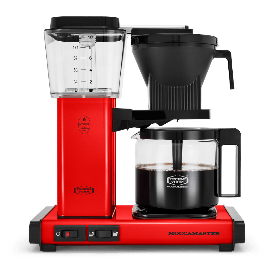 Front shot showing Moccamaster KBGV Select in Red, with rectangular tower and base, clear acrylic water reservoir with fill level marks, power and volume selector switch, glass carafe with black handle, and black automatic brew basket.